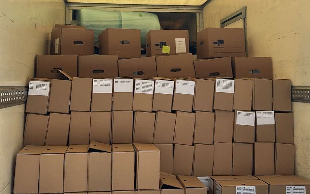 Cardboard moving boxes stacked wall to wall inside a box truck, with a flat hand dolly at the bottom edge